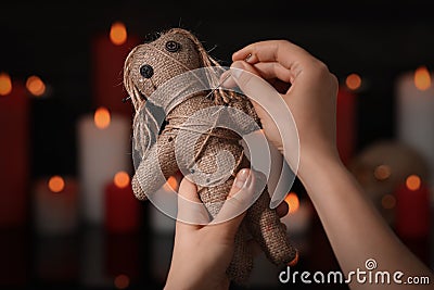 Woman stabbing voodoo doll with pin in dark room, closeup. Curse ceremony Stock Photo