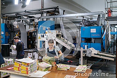 Woman stacking magazines on print shop Editorial Stock Photo