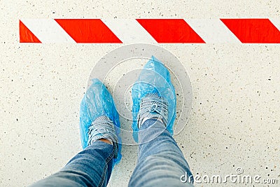 Woman stand in line keeping social distance wearing overshoes, medical shoe covers in hospital.Top view man standing behind a Stock Photo