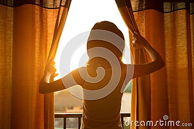 Woman stand in the room open curtain see sunrise Stock Photo