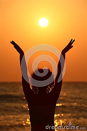 Woman standing on beach, raises hands Stock Photo