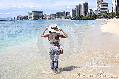 A woman standing on the beach wearing straw hat and leopard pants Stock Photo