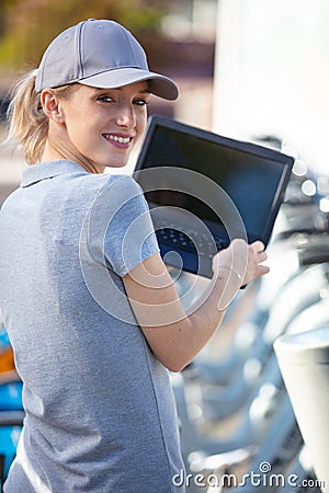 woman standing with city rent bicycle working with laptop Stock Photo