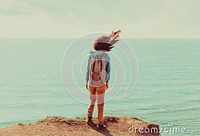 Woman standing on coastline in windy weather Stock Photo
