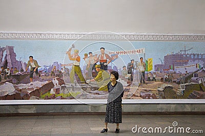 Woman standing in front of socialist realist mosaic at Pyongyang Metro in North Korea Editorial Stock Photo