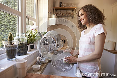 Woman Standing At Kitchen Sink Washing Up Stock Photo