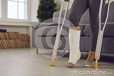 Woman standing with metal medical elbow crutches and showing broken injured leg Stock Photo