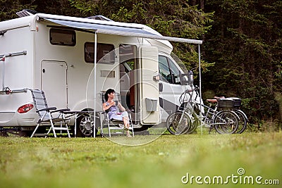 Woman is standing with a mug of coffee near the camper RV. Stock Photo