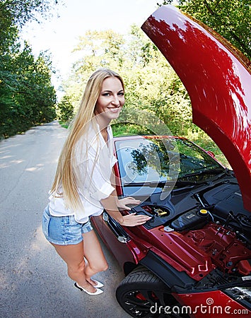 Woman standing near the opened hood of the broken cabriolet Stock Photo