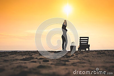 Woman standing near sun lounger and taking off her clother. Beach at sunset Stock Photo