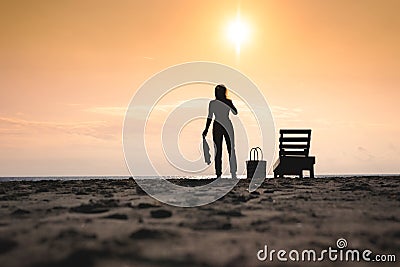 Woman standing near sun lounger and taking off her clother. Beach at sunset Stock Photo