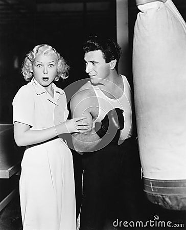 Woman standing next to a boxer feeling his arms and being astonished Stock Photo