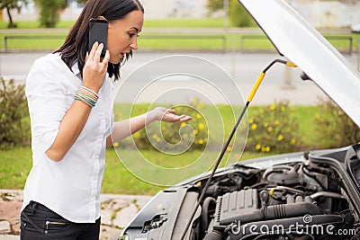 Woman standing next to broken car and talking on phone Stock Photo