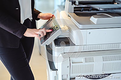 Woman pressing button on a copy machine in the office Stock Photo