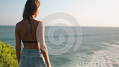 Woman standing on rocky cliff edge Banawa beach. Fit Caucasian Girl Contemplating Ocean Waves Crashing Camera Zoom in. Indonesia Vacation. Wild Sumba Island stock footage Woman standing on rocky cliff edge Banawa beach. Fit Caucasian Girl Contemplating Ocean Waves Crashing Camera Zoom in. Indonesia Vacation. Wild Sumba Island stock footage