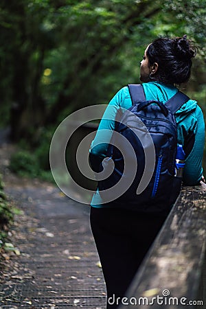 Woman standing on the side of a bridge in the middle of the woods. Ecotourism concept Stock Photo