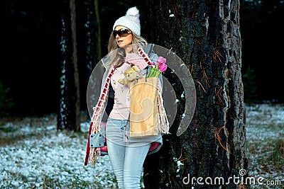 Woman standing in the snow under big old growth pine trees Stock Photo