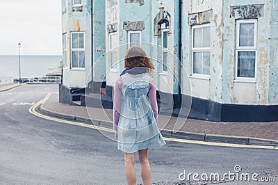 Woman standing in street outside blue house Stock Photo