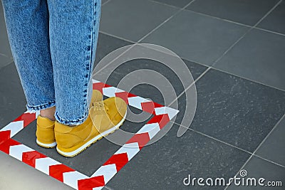 Woman standing on taped floor marking for social distance. Coronavirus pandemic Stock Photo