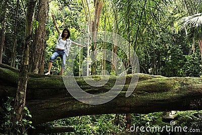 Woman standing on a tree in a tropical forest Stock Photo