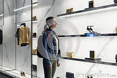 Woman stands at a boutique window and looks at shoes. Stock Photo