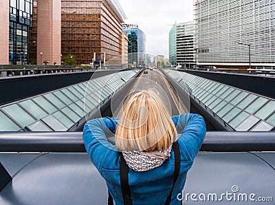 A woman stands on a bridge with her back to the camera against the background of a modern office quarter, Belgium Stock Photo