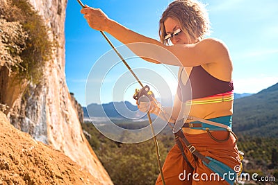 Woman stands on a large rock and belays the climber Stock Photo