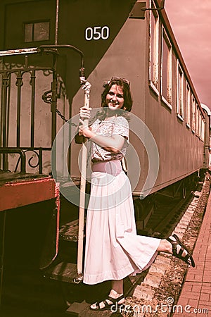 Woman stands on the steps of the cars train. The vintage train is at the station Stock Photo