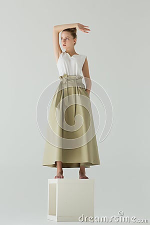 A woman stands in the studio on a white cube. Stock Photo