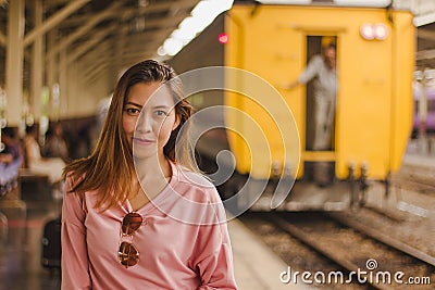 A woman stands with a train in the station. Stock Photo