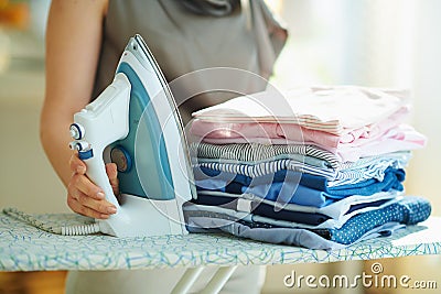 Woman with steam iron, ironing board and ironed clothes Stock Photo