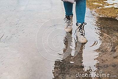 A woman steps into a puddle. Splashes of water scatter from under the feet Stock Photo