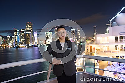 Woman steward on ship board at night in miami, usa. Sensual woman in suit jacket on city skyline. Water transport, transportation. Stock Photo