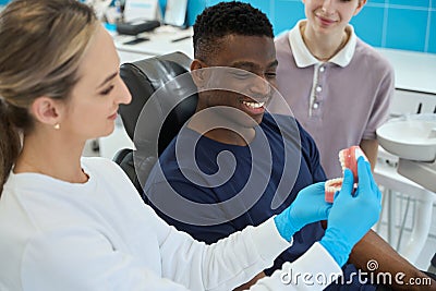 Woman stomatologist showing to male client work of jaw and teeth Stock Photo