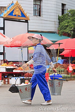 Woman on the street carrying two buckets in Ruili, Yunnan Province, China Editorial Stock Photo