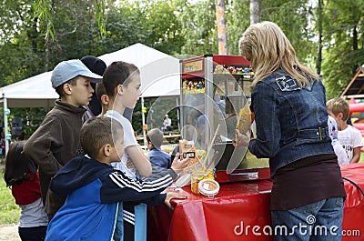 Woman street seller selling fast food for children standing in a line in front of a food moving store Editorial Stock Photo