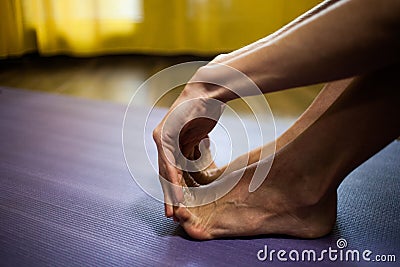 Woman stretch her feet to improve flexibility and mobility close up .at home natural light Stock Photo