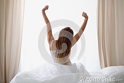 Woman stretching in bed after wake up, back view, entering a day happy and relaxed after good night sleep. Sweet dreams Stock Photo