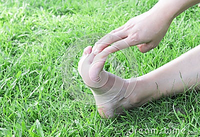 Woman stretching exercises feet finger on green grass background Stock Photo