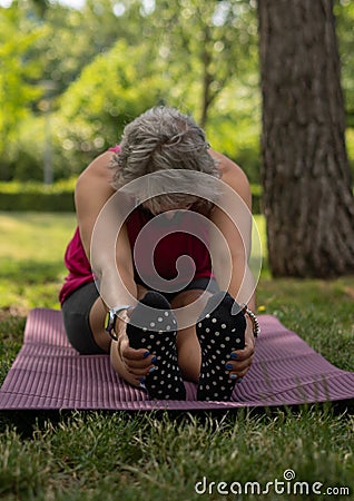 Woman stretching in a park, touching both feet Stock Photo