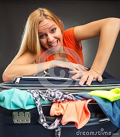 Woman struggles to shut a full suitcase Stock Photo