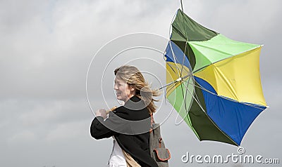 Woman struggling to hold her umbrella on a windy day Stock Photo