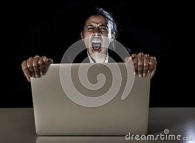 Woman or student girl working on laptop computer late at night holding the screen screaming Stock Photo