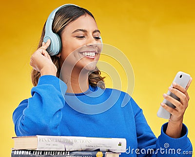 Woman, student and phone in studio with headphones, books and thinking with smile by yellow background. Gen z girl Stock Photo