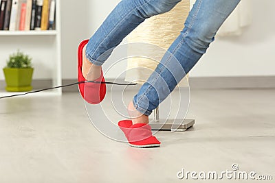 Woman stumbling with an electrical cord at home Stock Photo