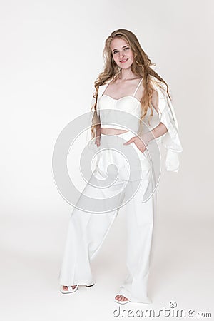 Woman stylishly dressed in white suit jacket, sculpting cupped corset top, trousers and slingbacks Stock Photo