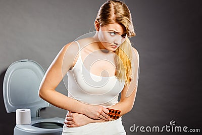 Woman suffer from belly pain holds pills in toilet Stock Photo