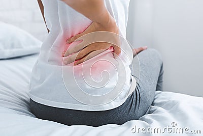 Woman suffering from back pain, sitting on bed Stock Photo