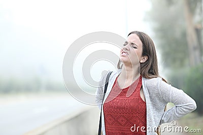 Woman suffering backache a foggy cold day Stock Photo