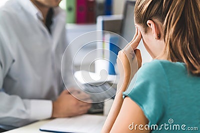 Woman suffering from bad headache or migraine. Appointment with doctor in office room. Stock Photo